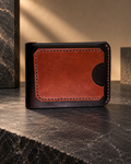 Premium handcrafted leather wallet in black and brown, featuring a dual-panel design, detailed stitching, and a textured center, displayed on a warm walnut wood surface.