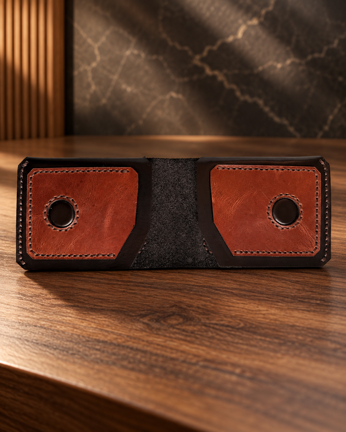 Premium handcrafted leather wallet in black and brown, featuring a dual-panel design, detailed stitching, and a textured center, displayed on a warm walnut wood surface.