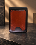 Premium handcrafted leather wallet in black and brown, featuring a dual-panel design, detailed stitching, and a textured center, displayed on a warm walnut wood surface.