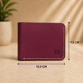 A burgundy leather wallet shown standing upright on a beige surface, with dimension lines and text indicating measurements of 10.5 cm width and 7.